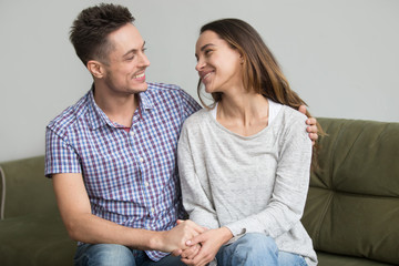 Happy smiling couple embracing and holding hands looking in each other eyes, reconciled after...