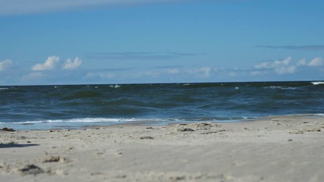 sandy beach, waves of the blue sea, blue sky. slow motion