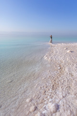 Fototapeta na wymiar Blonde young woman in a long skirt on the shore of the dead sea. Jordan