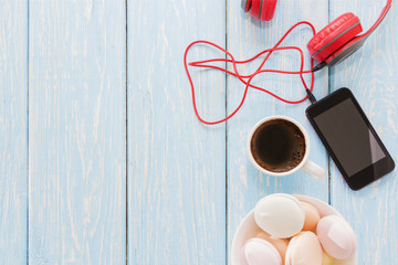 the marshmallow is next to the phone and red headphones and a Cup of black coffee. Coffee-break. Pleasant music.