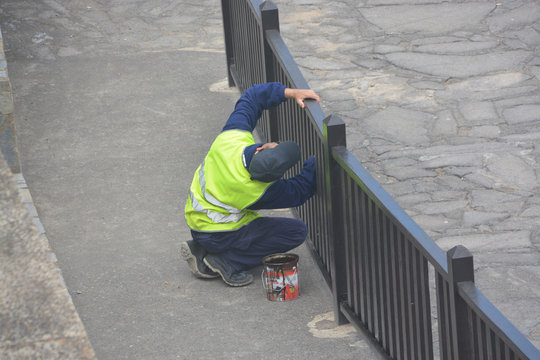 obrero reparando pintando una barandilla