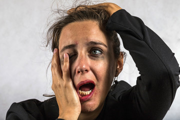 Desperate woman crying disheveled with pale eyes with makeup clouded perhaps by depression or gender violence. Image rich in detail