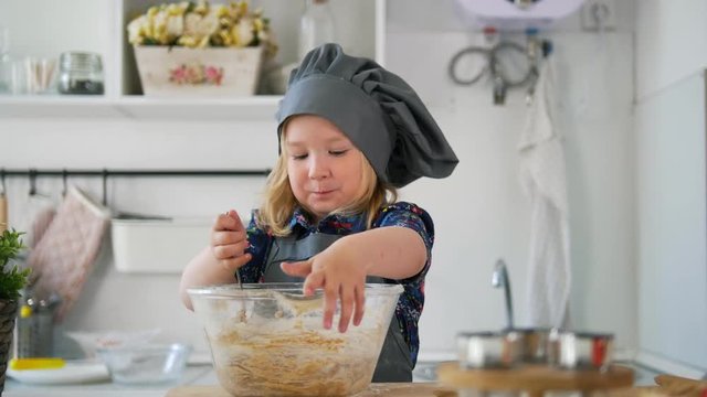 Preschool girl baker mixes the dough in a bowl