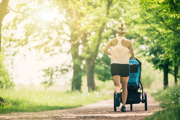 Running woman with baby stroller enjoying summer in park - 205290499