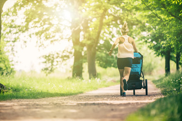 Running woman with baby stroller enjoying summer in park - 205290820