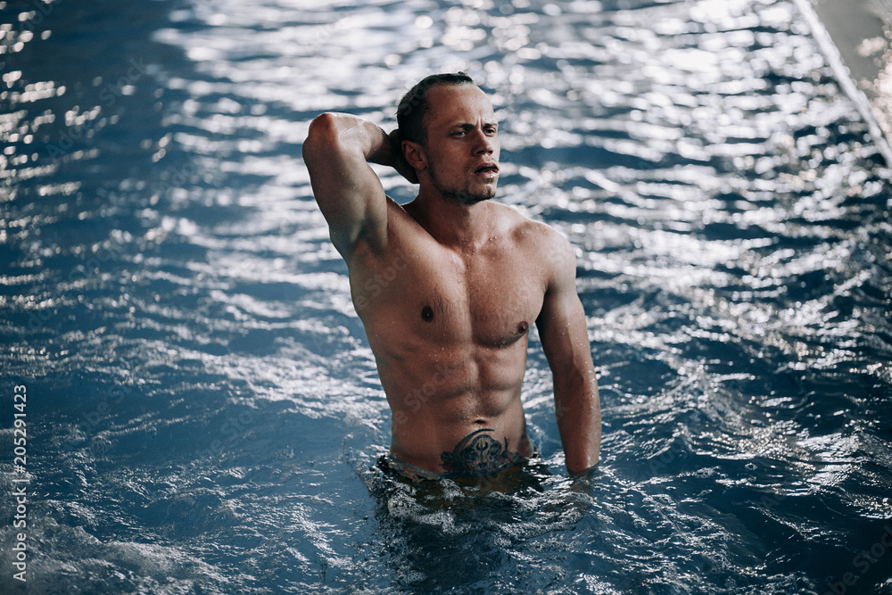 Wall mural sexy male model posing in swimming pool