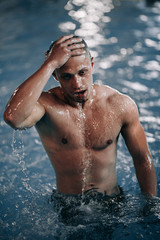 Sexy male model posing in swimming pool