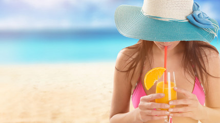 Woman in bikini and sun hat relaxing at sunny beach.