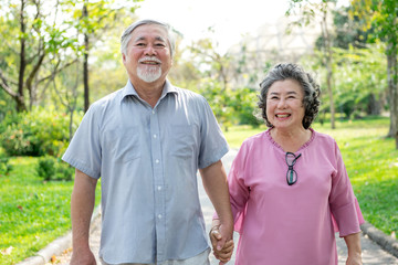 Senior couple in park portrait. Chinese old couple in park, relaxing, smiling. Medium shot.