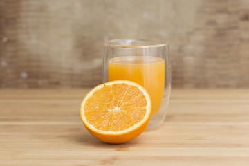 Natural orange juice with open half orange fruit on a wooden background