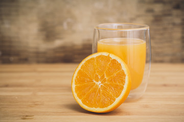 Orange juice served on a transparent glass and half orange slice raw fruit isolated on a wooden background