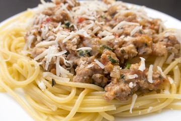 Appetizing spaghetti in a plate with Bolognese sauce on a dark background close up