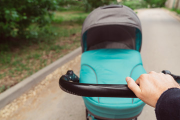 A man is walking with a baby stroller in the park. Father's Day and Mother's Day.