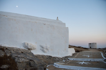 A small chapel and behind a windmill at the top of the mountain in Amorgos