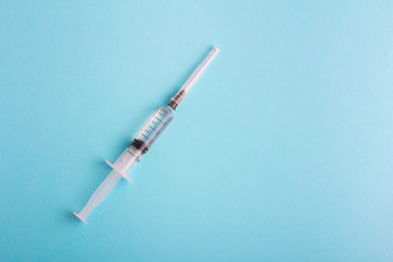 Syringe with lid on blue background. Copy space