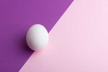 Chicken egg on purple pink diagonal flat lay background. Copy space