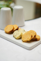 Butter flavored with herbs and spices on ceramic cutting board, close-up. 