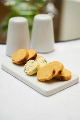 Butter flavored with herbs and spices on ceramic cutting board, close-up. 