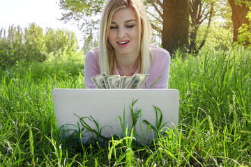 girl counts money in front of a laptop screen, outdoors