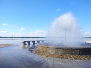 Fountain in the form of a ball on the river, a view of the waterfront with a blue sky, a landscape with a fountain and a river. Copy space