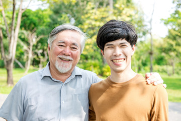 Father and son in park portrait. Retired chinese father with his son holding each other, happy and smiling. Successful family love and relationship concept.