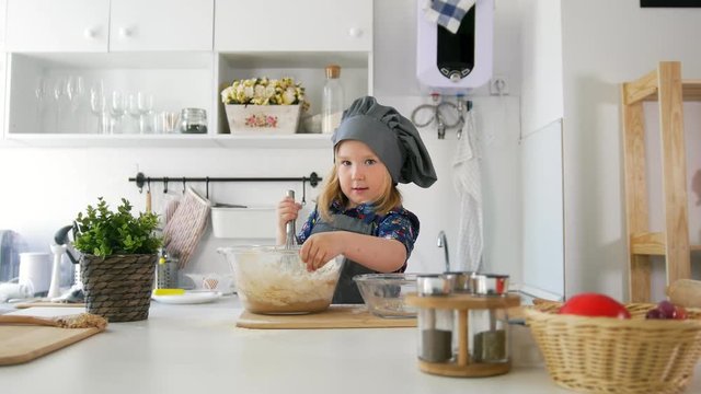 Girl baker mixes the mixture for cookies with a whisk