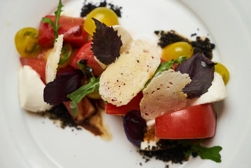 Vegetarian food with marinated tomatoes, arugula, mozzarella cheese, balsamic jelly, olive oil. Delicious healthy food concept, close-up