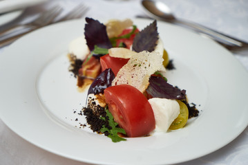 Vegetarian food with marinated tomatoes, arugula, mozzarella cheese, balsamic jelly, olive oil. Delicious healthy food concept, close-up