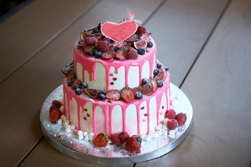 Cake with fresh berries and cream on old wooden background.