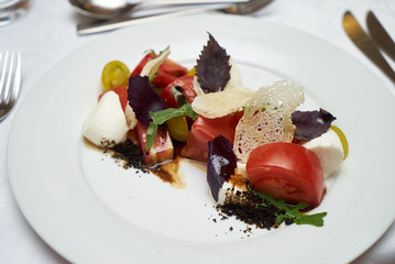 Vegetarian food with marinated tomatoes, arugula, mozzarella cheese, balsamic jelly, olive oil. Delicious healthy food concept, close-up