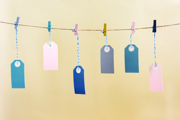 On the rope, with crumpled colored clothespins, they hang around in the puffs. A place for an inscription, mock up. Photo on a pale yellow background.