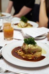 People eating roasted organic chicken dish with tarragon, mustard sauce, rosemary, potatoes tian and confit fennel, close-up. Delicious healthy food dinner on serving table concept