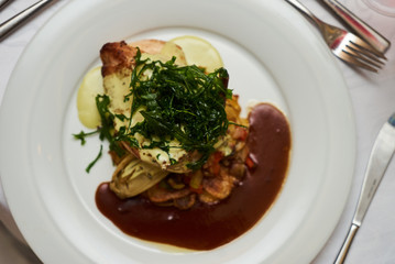 People eating roasted organic chicken dish with tarragon, mustard sauce, rosemary, potatoes tian and confit fennel, close-up. Delicious healthy food dinner on serving table concept