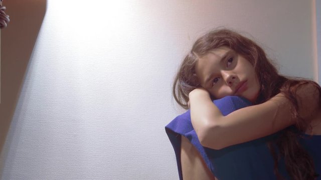 sad girl upset embraces her feet. is depressed and suicidal little lamentable girl schoolgirl sadness misses the night in bed concept childhood family. the problem of education in the family