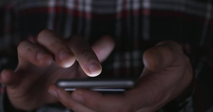 Online gambling: a close up of a man placing a bet via online gambling on his phone late at night and crossing his fingers for good luck. 4k Slow motion.
