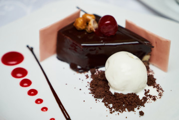 Black forest Cake with cherry, vanilla ice-cream, chocolate and cup of hot tea on table. Delicious sweet dessert breakfast on table background, close-up
