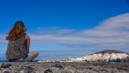 mädchen im Schneidersitz schaut auf die Küstenstadt