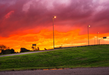 Atardecer en la ruta junto a las luces y el cielo naranja amarillo rojizo rojo y violeta