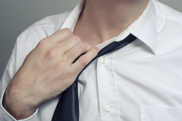 Man in white shirt taking off necktie