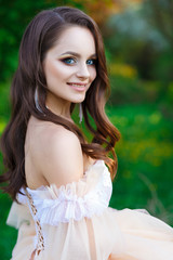 Naklejka premium Young beautiful girl in a blooming apple orchard. Bride in a wedding dress in the garden