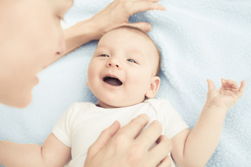 Cute baby boy playing with his mother on bed. 