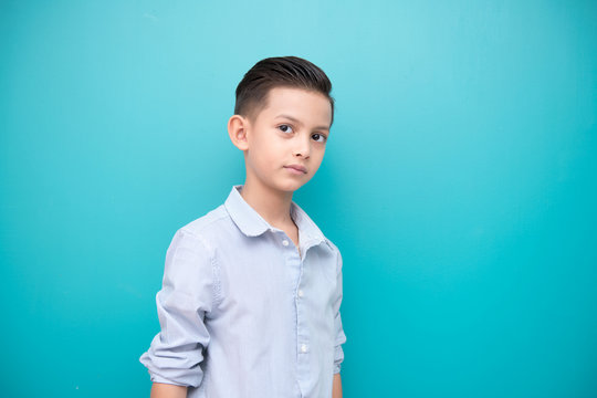 Young boy isolated in blue. Handsome early teenage boy portrait. Cool looking pose.