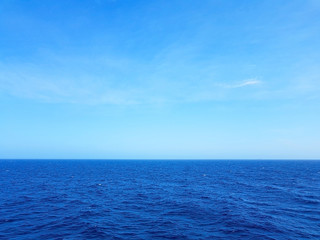 view of the ocean and blue sky with waves in the middle of the sea and white foam