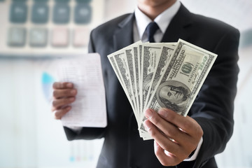 Businessman holding money on hand, Spreading one hundred US Dollar bills in financial concepts, Selective focus.