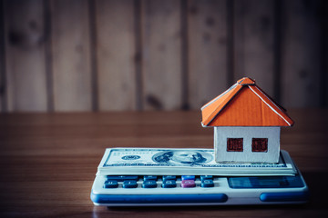 House from the paper with money and calculator on wooden background