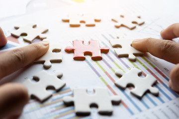 Closeup of businessman and woman with jigsaw puzzle pieces in office