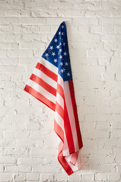 united states of america flag hanging on white brick wall