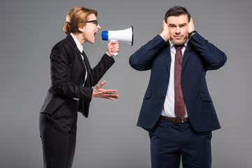 angry businesswoman with bullhorn screaming at businessman, isolated on grey, feminism concept