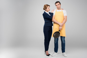 businesswoman and male upset householder with frying pan hugging together, feminism concept,...