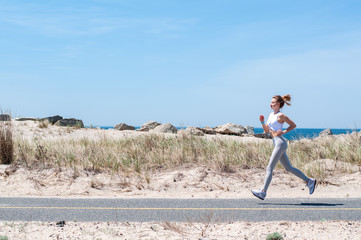 Fitness woman running on beach.